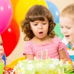 kids celebrating birthday party and blowing candles on cake